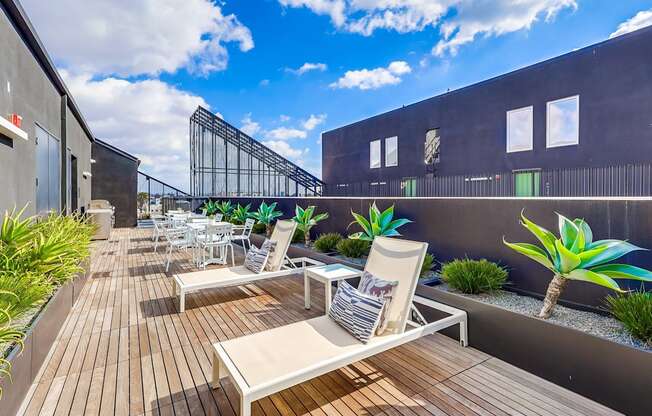 A patio with white chairs and a wooden table.