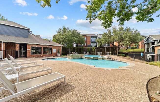 A pool surrounded by a gravel area and trees.