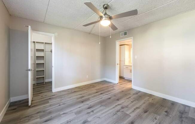 an empty living room with a ceiling fan and a closet