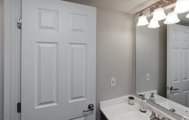 a bathroom with a sink and a mirror and a door