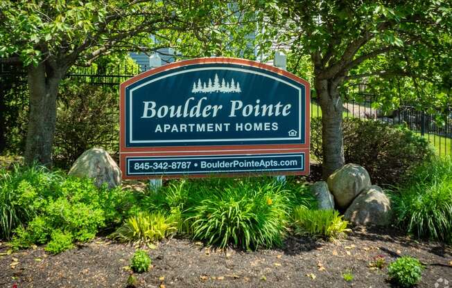 a sign for boulder pointe apartment homes in front of trees