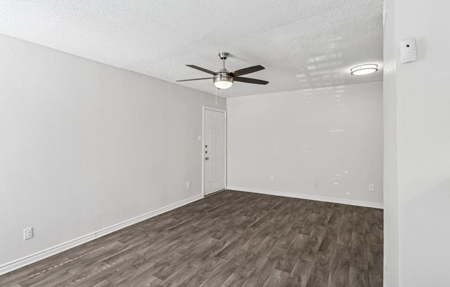 A living room with a ceiling fan and wooden flooring.