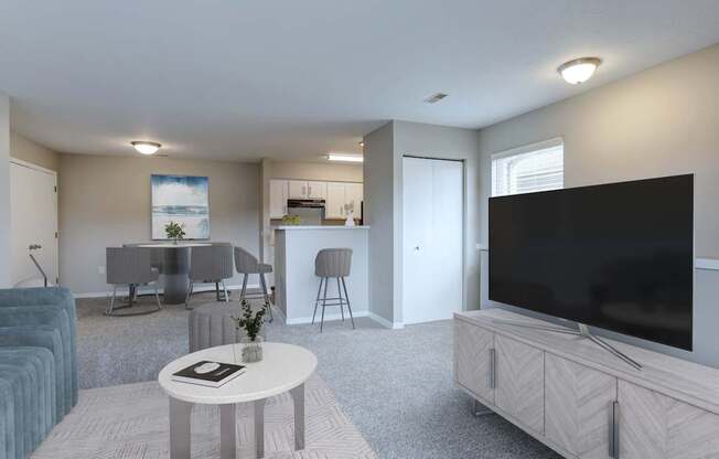 A living room with a grey couch, a white coffee table, and a large flat screen TV.