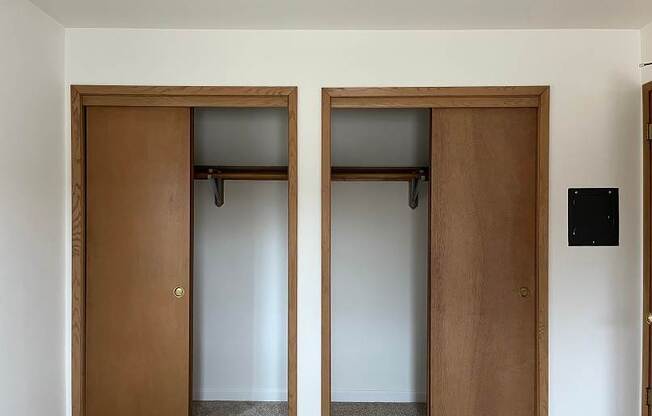 Two brown doors with windows in a white room.