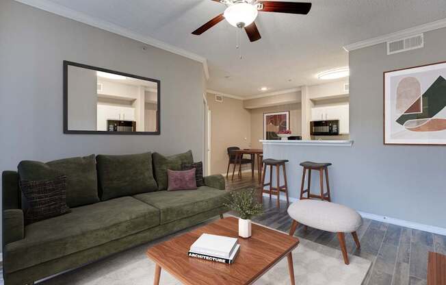 A living room with a green couch, a wooden coffee table, and a mirror on the wall.