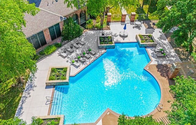 an aerial view of a resort style pool with chairs and trees