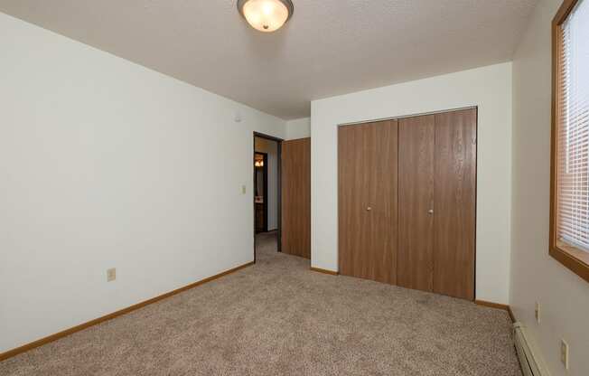 A bedroom with carpet and a closet. Fargo, ND Park Circle Apartments.