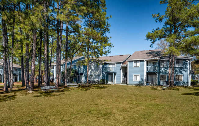 A large grassy area in front of a building with trees on the left.