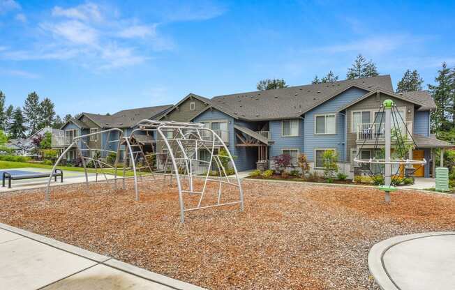 Climbing Area with Wood Chip Floor, Climbing Aparatus, and Blue Apartment Exteriors