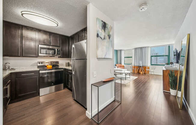 A modern kitchen with dark wood cabinets and stainless steel appliances.
