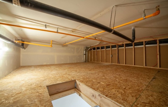 a large room with wood flooring and pipes in it