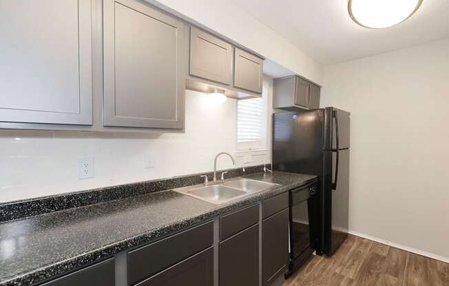 a kitchen with dark cabinets and a black refrigerator