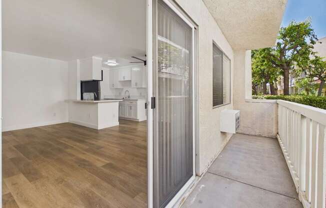 A balcony with a sliding glass door leading to a kitchen.