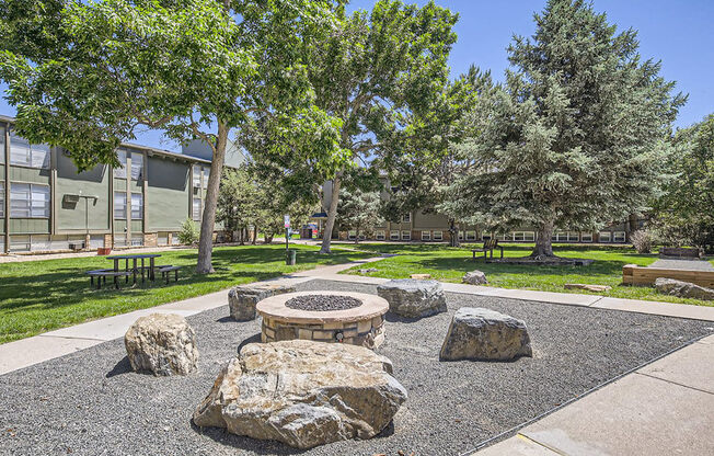 a fire pit with rocks and trees in a park