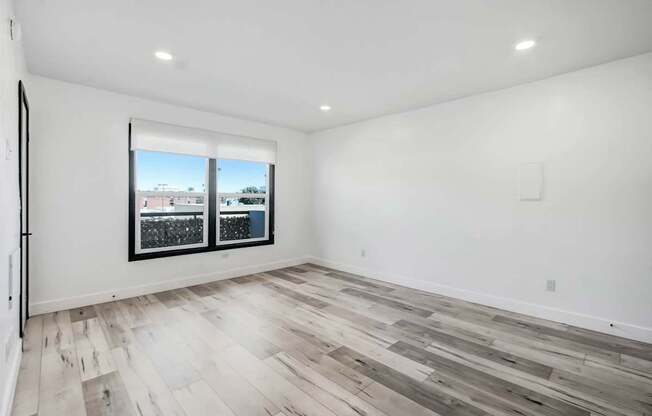A room with a window and a wooden floor.