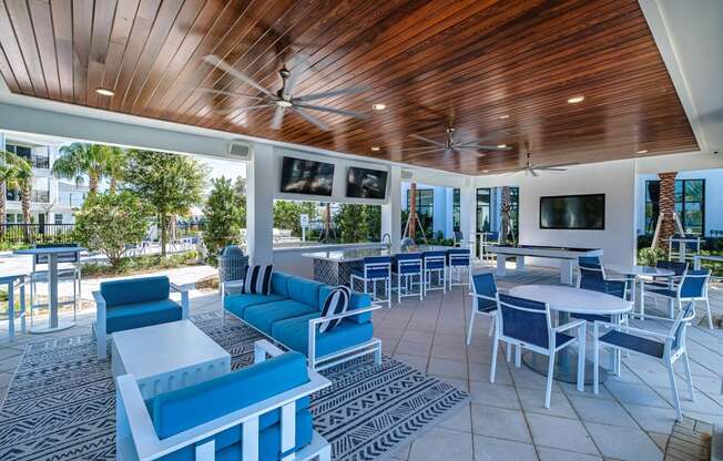 a lounge area with blue chairs and tables and a pool at Altis Grand Suncoast, Florida, 34638