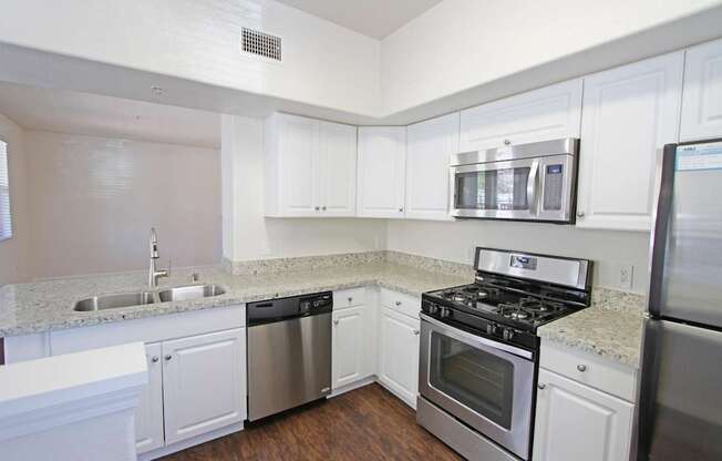 A kitchen with white cabinets and stainless steel appliances at The Kitt at Warner Center Apartments, California, 91303