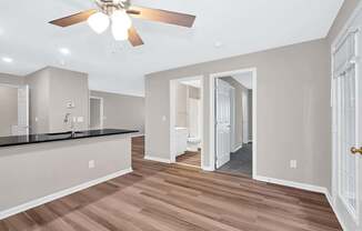 A spacious kitchen with a ceiling fan and wooden flooring.
