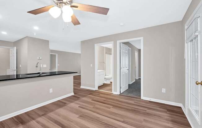A spacious kitchen with a ceiling fan and wooden flooring.