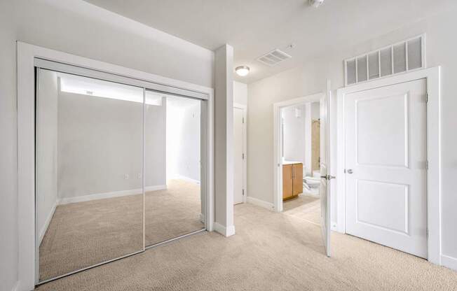 A room with a white door and a mirror on the wall.