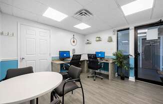 A room with a white table and chairs, a white door, and a window with blinds.