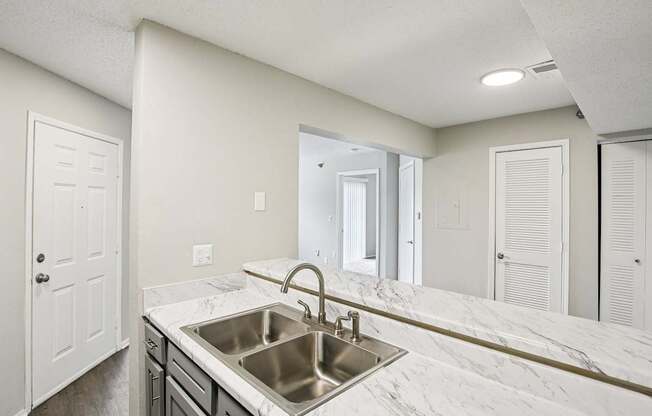 A kitchen with a marble countertop and stainless steel sink.