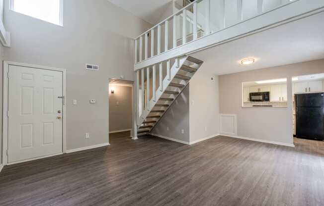 an empty living room with a staircase in the middle