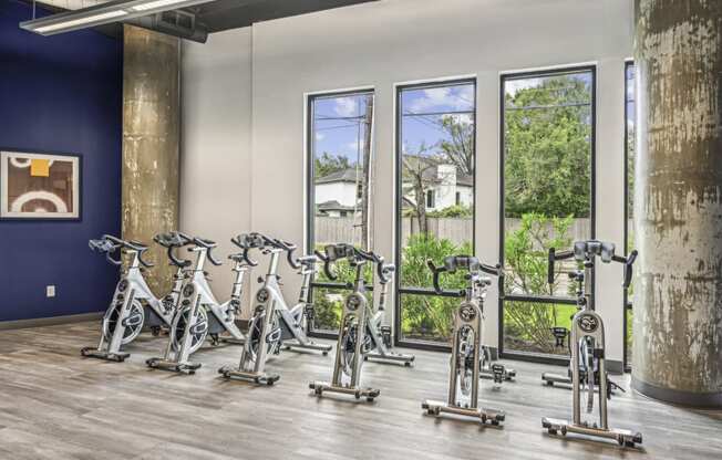 Spin bike area with large windows and mirrored wall at Allusion at West University apartments in Houston, TX