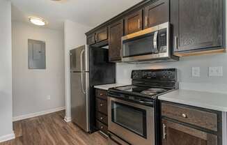 a kitchen with black appliances and wooden cabinets and a stainless steel refrigerator