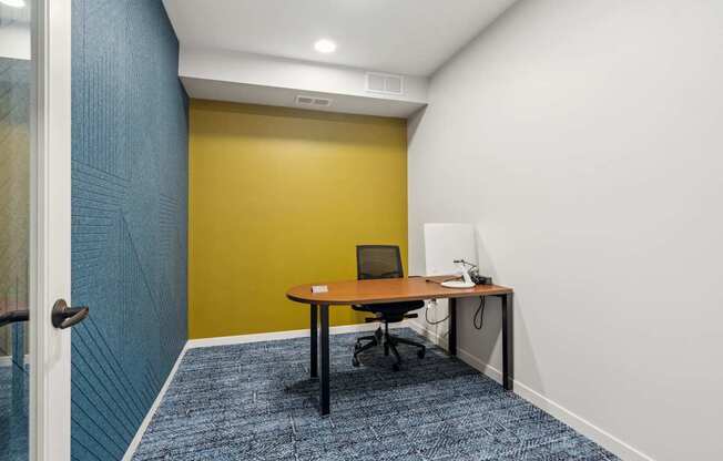 A room with a yellow wall and a desk with a laptop on it.