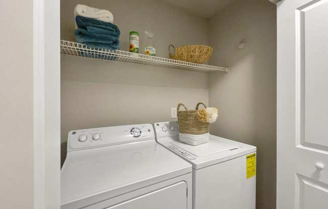 a washer and dryer in a small laundry room with a shelf over the