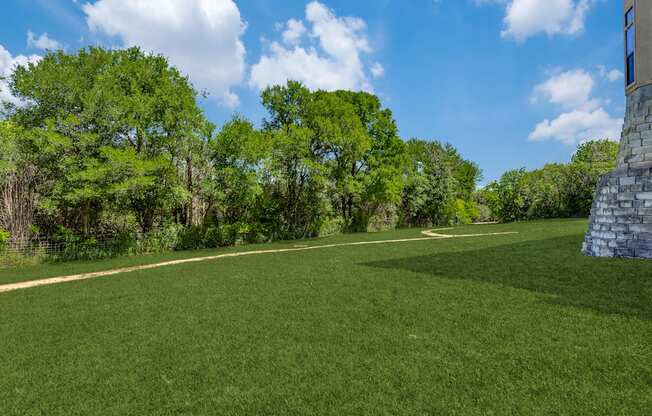 a large grassy field with trees and a building on the side