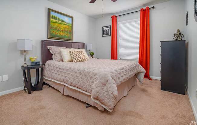 a bedroom with a bed and a window with red curtains