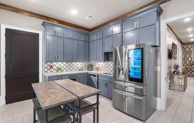 A kitchen with a table and chairs in front of a refrigerator.