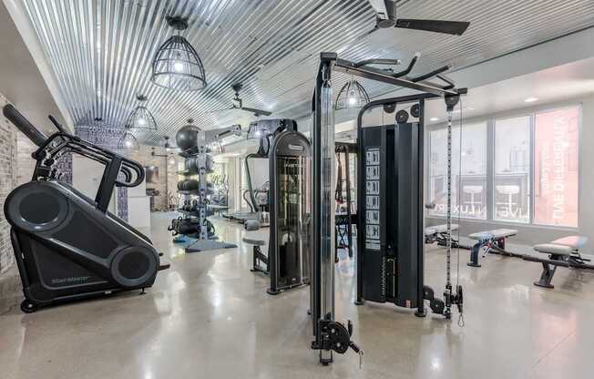 A gym with a variety of equipment including a treadmill, a stationary bike, and a rowing machine.