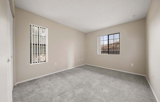 A room with a carpeted floor, a window with bars, and a door.