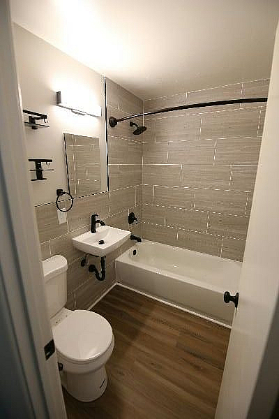 Modern bathroom with elegant wood flooring, sleek tiled walls, and contemporary fixtures.