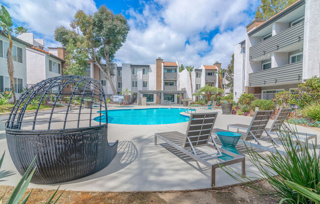 a pool with chairs and a hammock in front of an apartment building at City View Apartments at Warner Center, Woodland Hills California