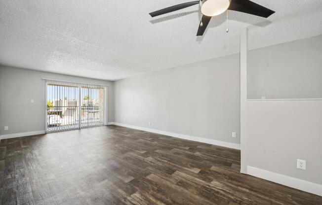 A room with a ceiling fan and wooden flooring.