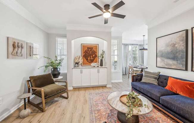 A living room with a blue couch and a wooden chair.