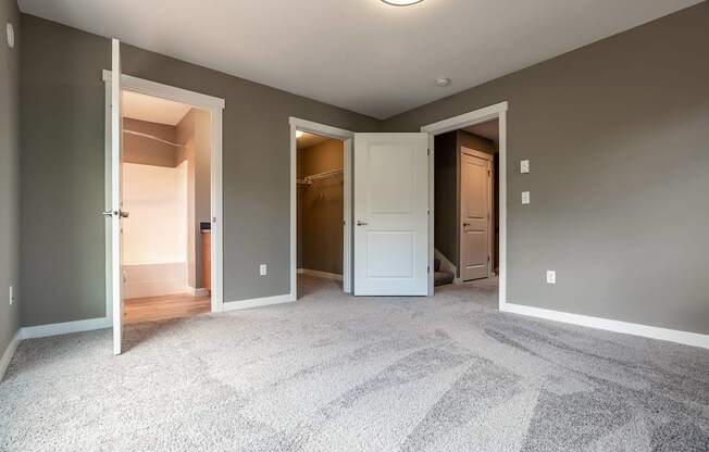 A room with a carpeted floor and three open doors.