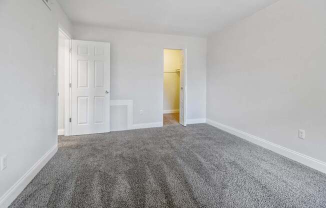A room with a carpeted floor and two doors, one of which is open.