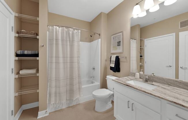 a bathroom with beige walls and a white sink and toilet next to a white shower curtain