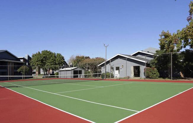 a tennis court with houses and trees in the background