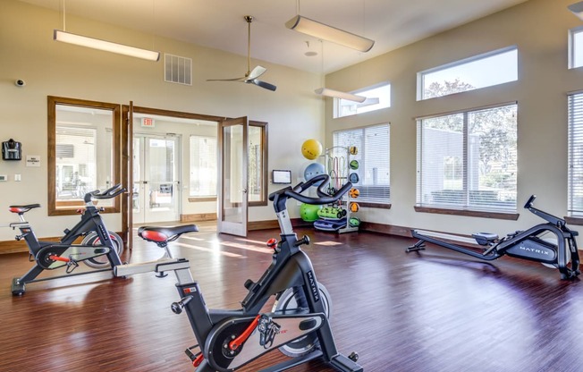 a gym with treadmills and exercise equipment in a room with windows