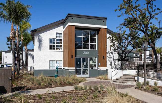 A modern building with a white facade and a brown door is surrounded by palm trees at Verandas Apartments, California