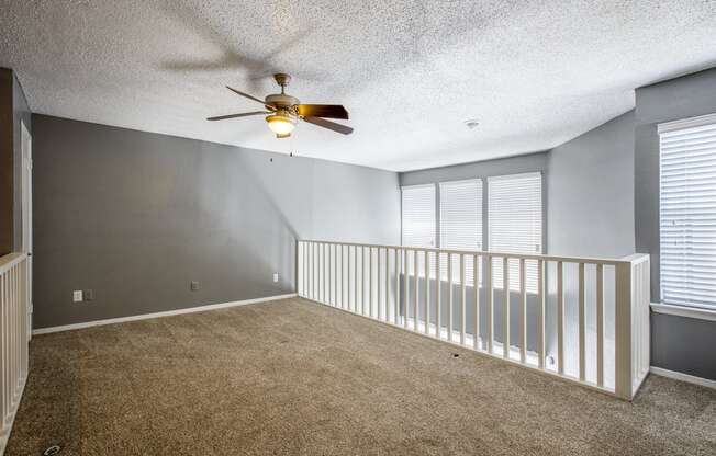 A room with a ceiling fan and carpeted floor.