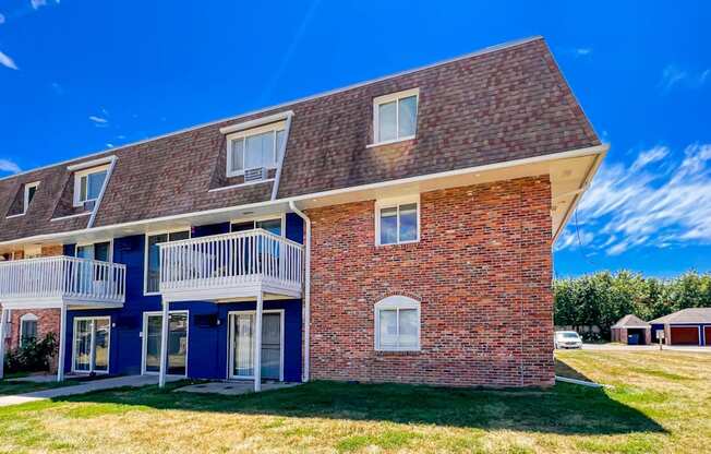 A red brick house with a blue door and white railings at The Hampton Meadows Apartments, Des Moines, IA