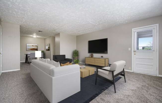 Omaha, NE Maple Ridge Apartments. A living room with white couches and chairs and a tv on the wall