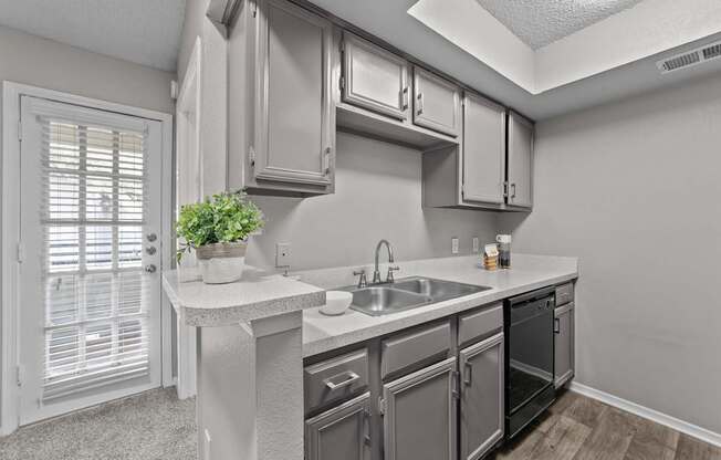 A kitchen with a sink, stove, and cabinets.